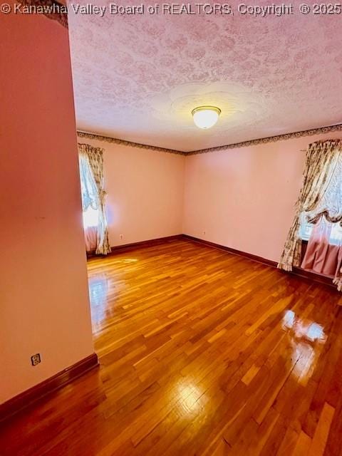 empty room featuring hardwood / wood-style floors, baseboards, and a textured ceiling