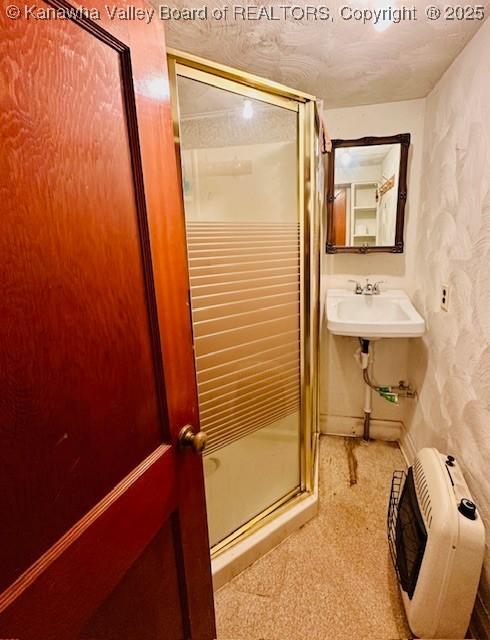 full bath with a sink, a textured ceiling, and a shower stall