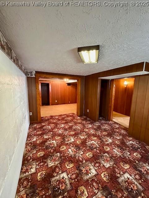 empty room with wood walls and a textured ceiling