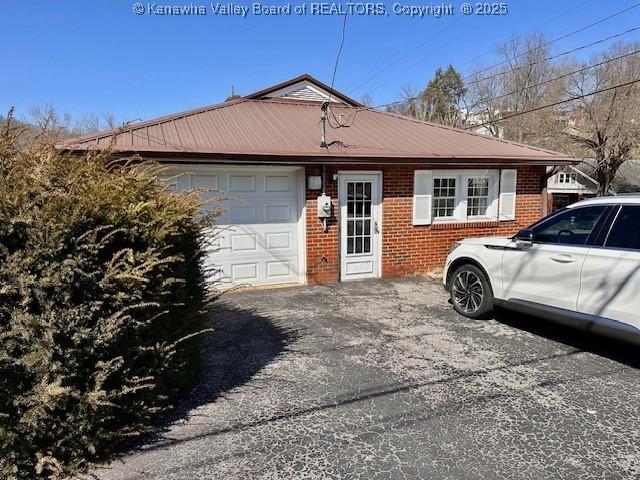 ranch-style home with an attached garage, brick siding, and driveway