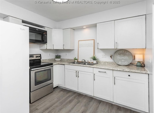 kitchen featuring a sink, freestanding refrigerator, stainless steel range with electric cooktop, white cabinets, and black microwave