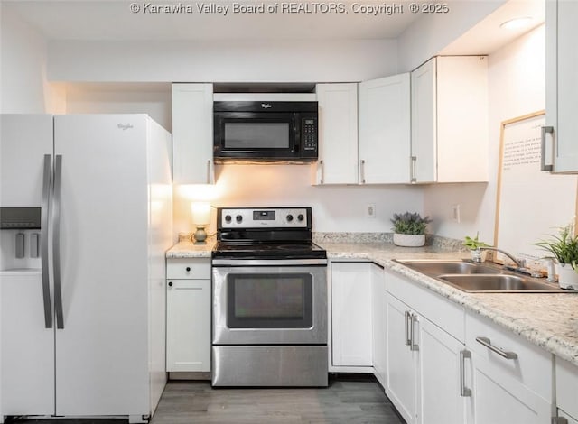 kitchen with black microwave, stainless steel electric range, white refrigerator with ice dispenser, white cabinets, and a sink