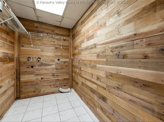 spare room featuring wooden walls, light tile patterned flooring, and a paneled ceiling