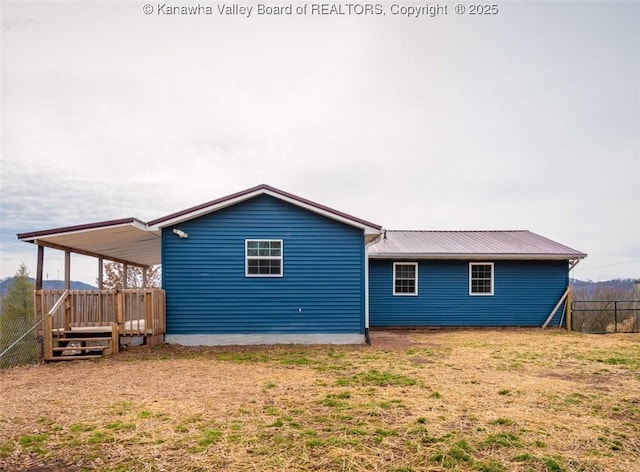 rear view of property with fence and metal roof