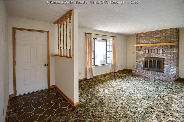 unfurnished living room with visible vents, a textured ceiling, dark carpet, baseboards, and a brick fireplace