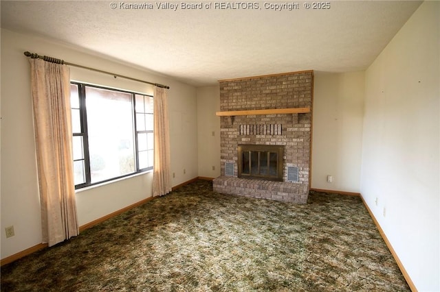 unfurnished living room featuring baseboards, carpet floors, a textured ceiling, and a brick fireplace