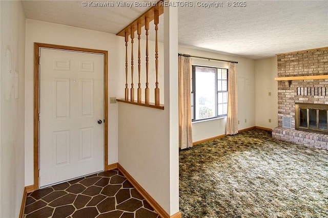 interior space with a brick fireplace, baseboards, and a textured ceiling