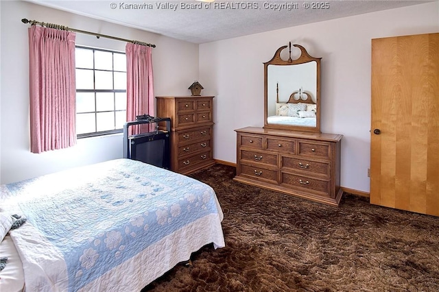 bedroom with baseboards, a textured ceiling, and dark carpet