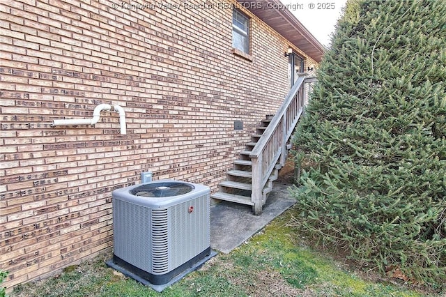 exterior details featuring brick siding, stairs, and central AC