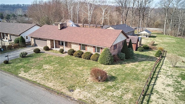 view of front of property featuring brick siding, driveway, a front lawn, and fence