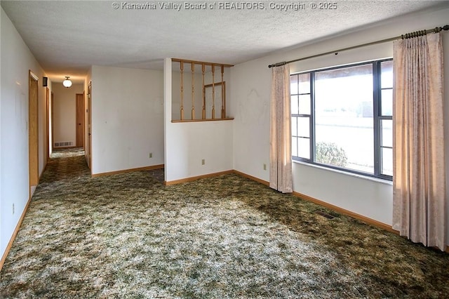 carpeted spare room with visible vents, baseboards, and a textured ceiling