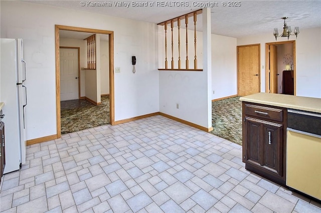 kitchen featuring baseboards, a chandelier, dark brown cabinetry, light countertops, and freestanding refrigerator