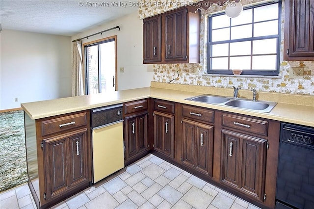 kitchen with dishwasher, a peninsula, light countertops, and a sink