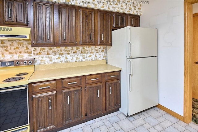 kitchen featuring electric stove, freestanding refrigerator, dark brown cabinetry, light countertops, and extractor fan