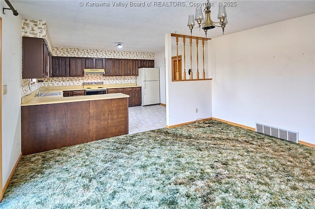 kitchen featuring visible vents, an inviting chandelier, freestanding refrigerator, a sink, and extractor fan