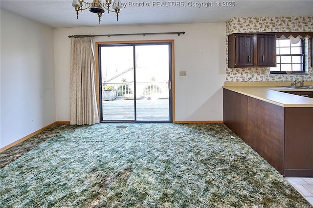 unfurnished dining area with light carpet, a notable chandelier, baseboards, and a textured ceiling