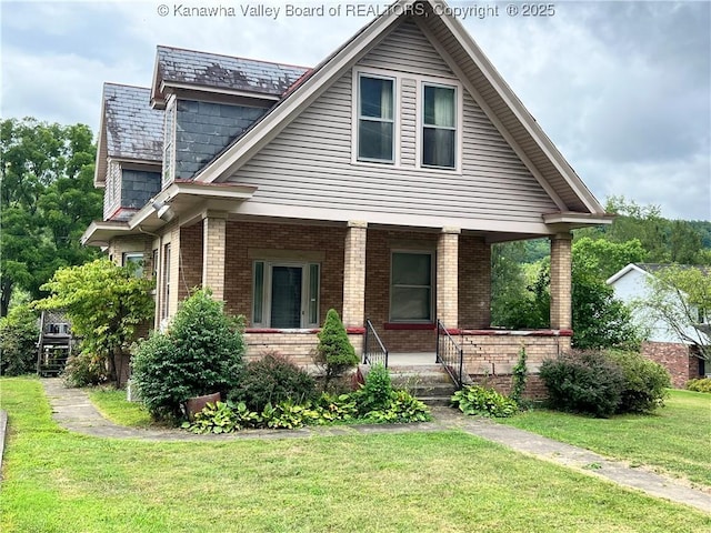 view of front of property featuring brick siding, covered porch, and a front yard