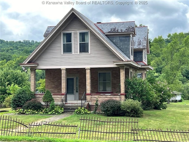 view of front of property featuring a front yard, covered porch, fence, and brick siding