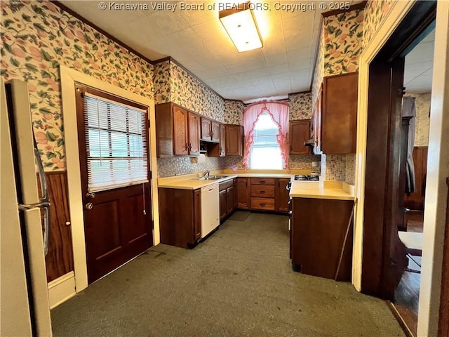 kitchen featuring wallpapered walls, freestanding refrigerator, light countertops, dishwasher, and gas range