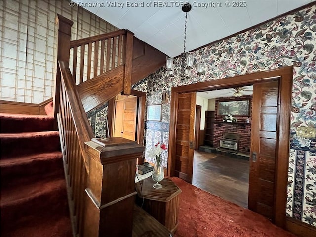 stairway with wallpapered walls, wood finished floors, and a ceiling fan