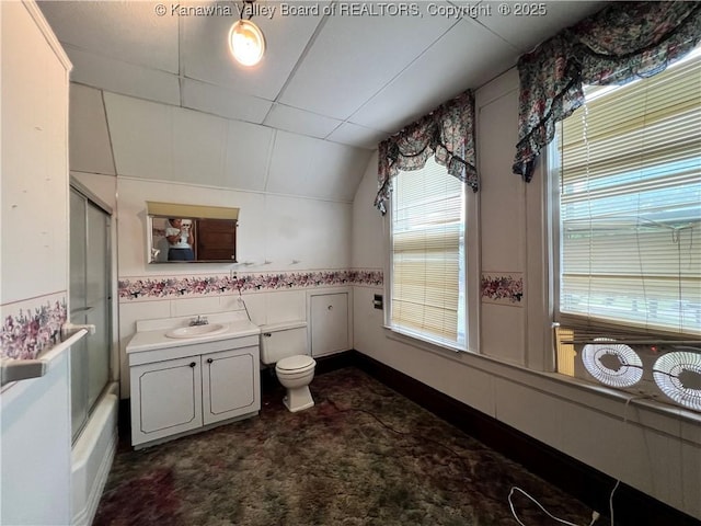 bathroom with vanity, shower / bath combination with glass door, vaulted ceiling, tile walls, and toilet