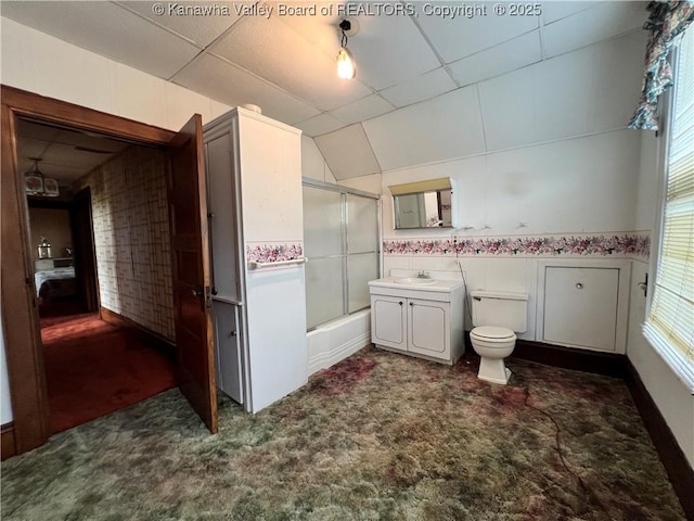 full bath with enclosed tub / shower combo, a drop ceiling, toilet, and vanity