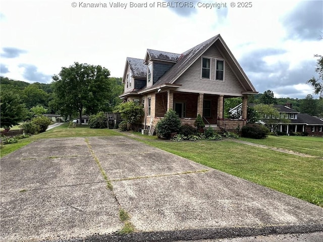 view of side of home with a yard, brick siding, and a porch