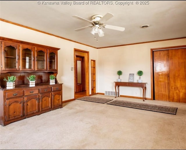 interior space featuring visible vents, light colored carpet, and crown molding