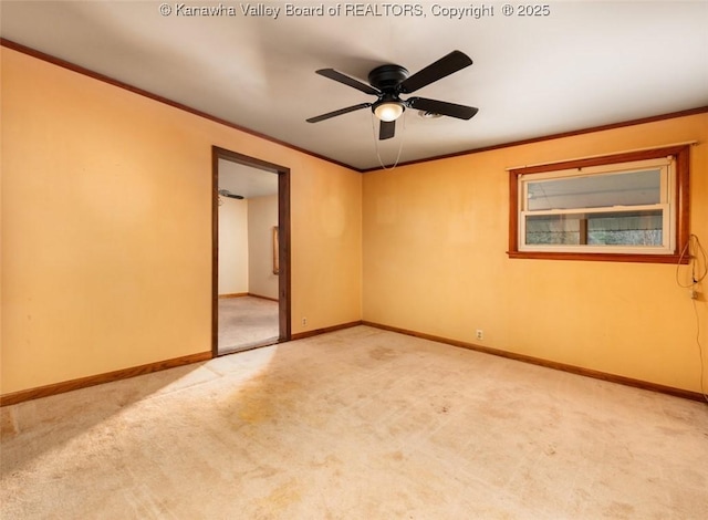 carpeted empty room with crown molding, baseboards, and ceiling fan