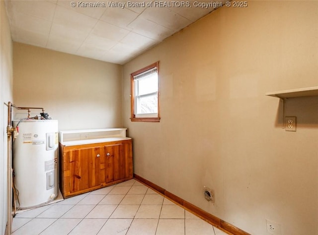 laundry area with baseboards, electric water heater, and light tile patterned flooring