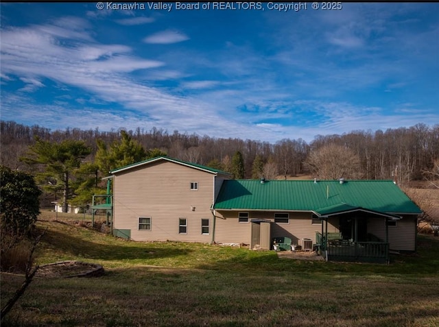 rear view of house featuring a lawn and metal roof