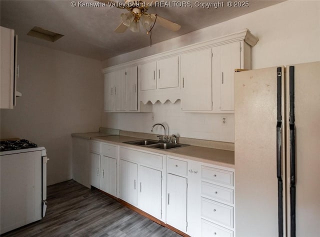 kitchen featuring dark wood-type flooring, light countertops, white appliances, a ceiling fan, and a sink