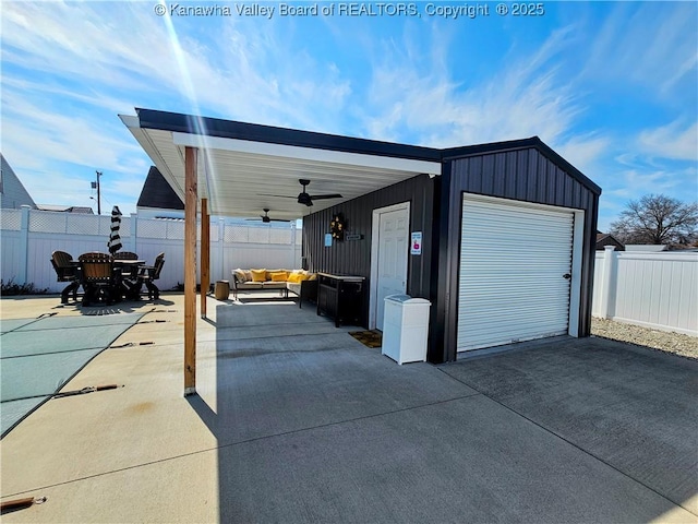 garage with ceiling fan, concrete driveway, and fence