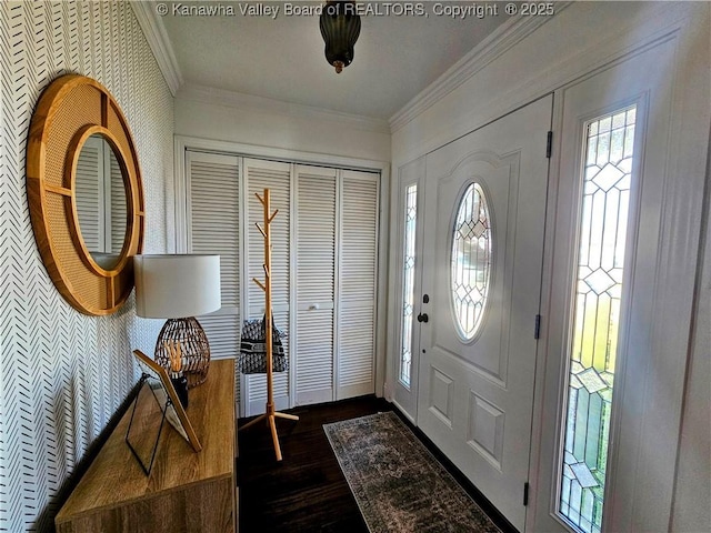 entrance foyer with dark wood-type flooring, ornamental molding, and wallpapered walls