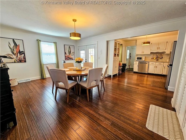 dining space with crown molding, dark wood-style floors, and a textured ceiling