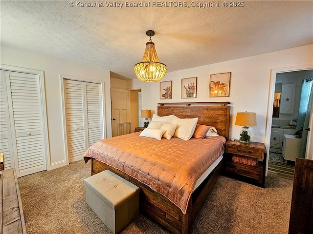 carpeted bedroom with an inviting chandelier, connected bathroom, multiple closets, and a textured ceiling