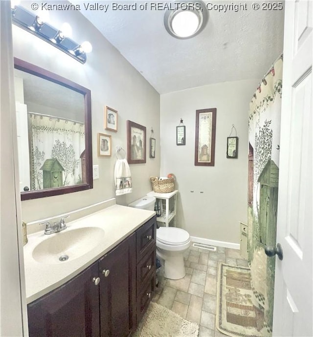 full bath with vanity, visible vents, baseboards, stone finish flooring, and toilet