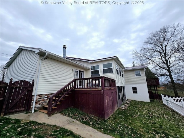 rear view of property featuring a gate, a lawn, a deck, and fence