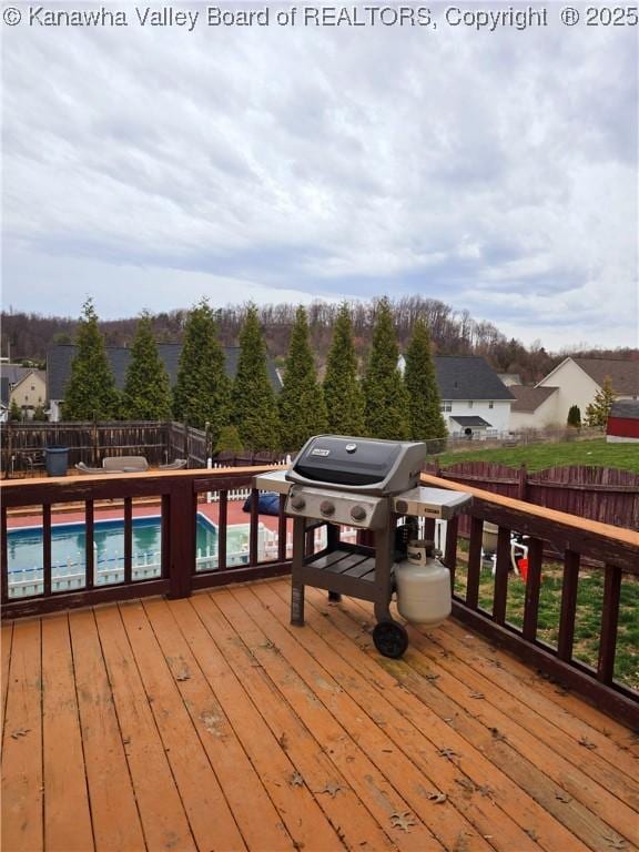 wooden terrace featuring a fenced in pool, a grill, and a fenced backyard