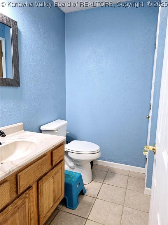 half bathroom with tile patterned floors, toilet, vanity, and baseboards