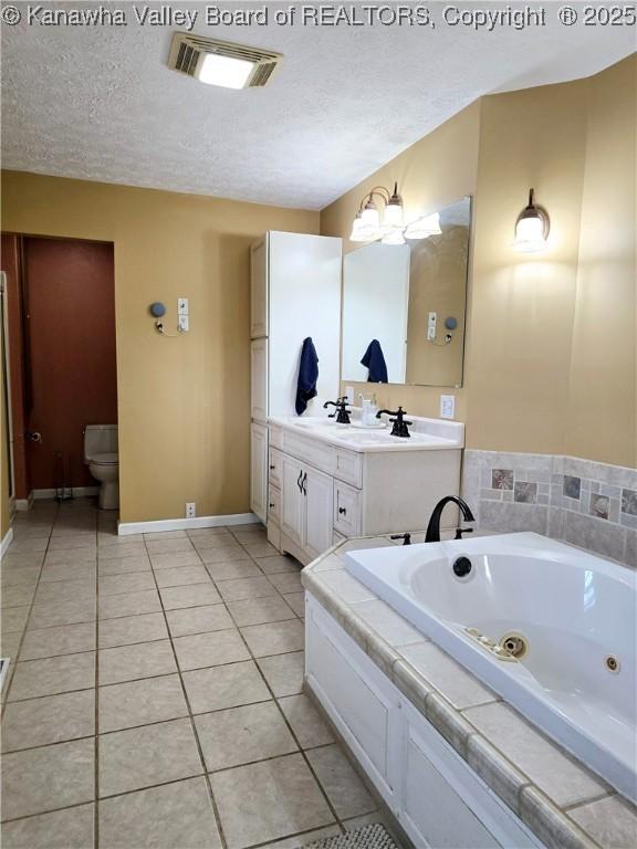 bathroom with tile patterned floors, visible vents, a textured ceiling, and a tub with jets