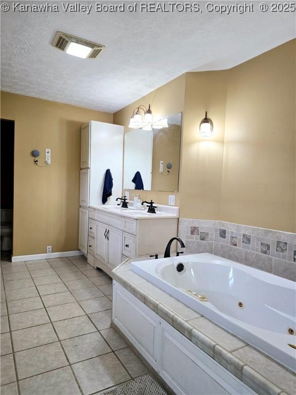 full bath featuring visible vents, a jetted tub, vanity, tile patterned floors, and a textured ceiling