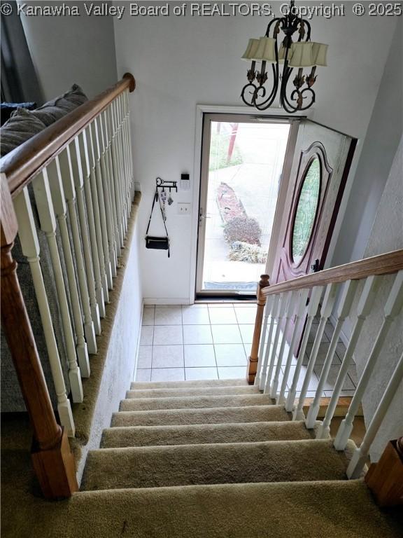 stairway with tile patterned flooring and a chandelier