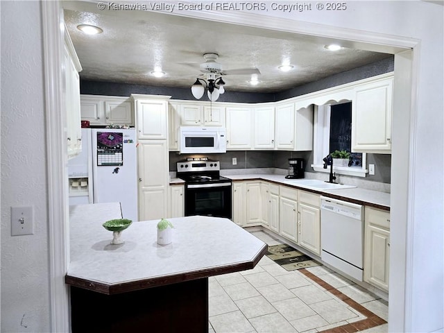 kitchen with white appliances, white cabinetry, a ceiling fan, and a sink