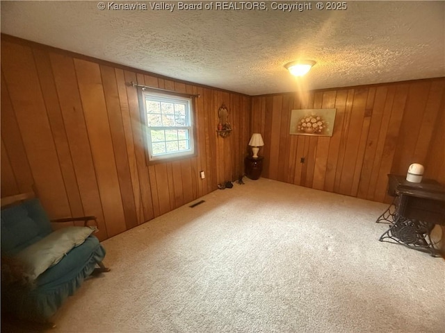 interior space with carpet flooring, visible vents, wood walls, and a textured ceiling