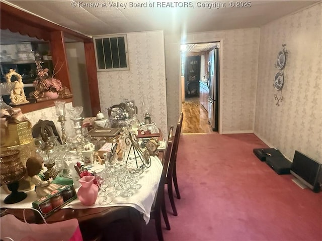 carpeted dining space with visible vents and wallpapered walls