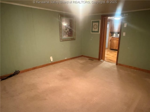 unfurnished room featuring baseboards, light colored carpet, and crown molding