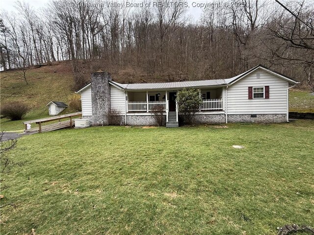 view of front facade featuring a front lawn, covered porch, metal roof, crawl space, and a chimney