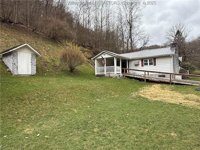exterior space with a storage unit, an outbuilding, a front lawn, metal roof, and a chimney