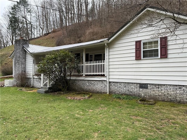 view of front of house featuring covered porch, a chimney, a front lawn, crawl space, and central air condition unit